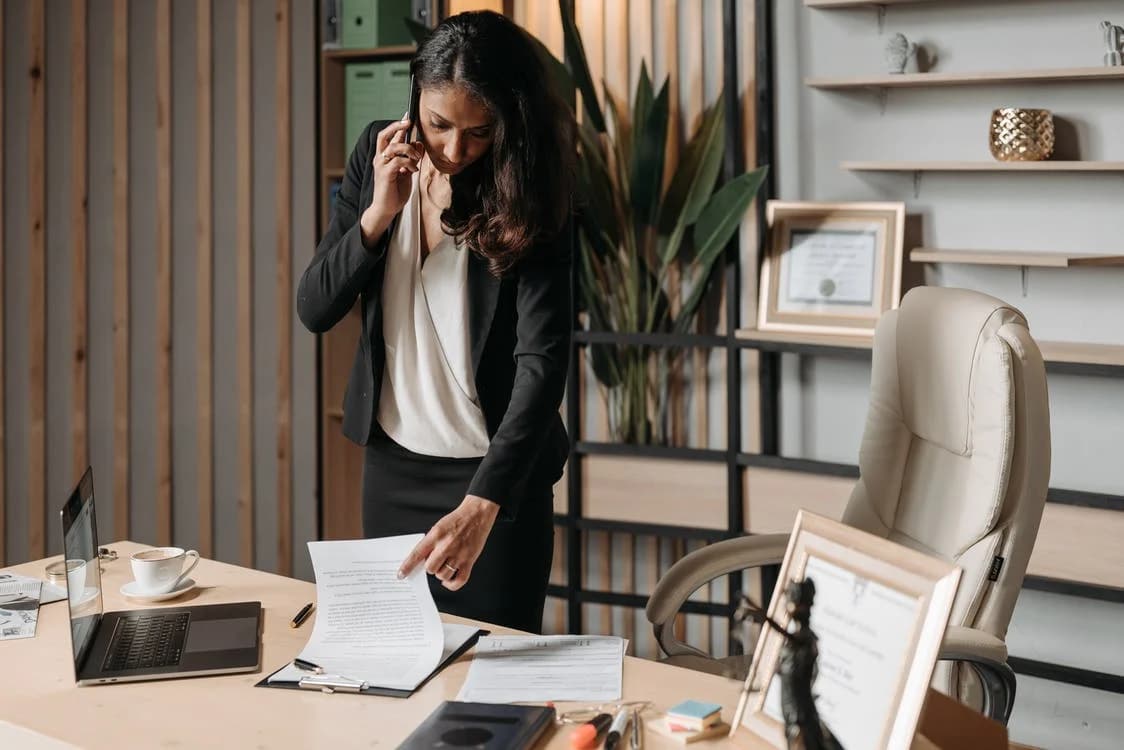 avocate au téléphone consulte un document sur son bureau dans son bureau