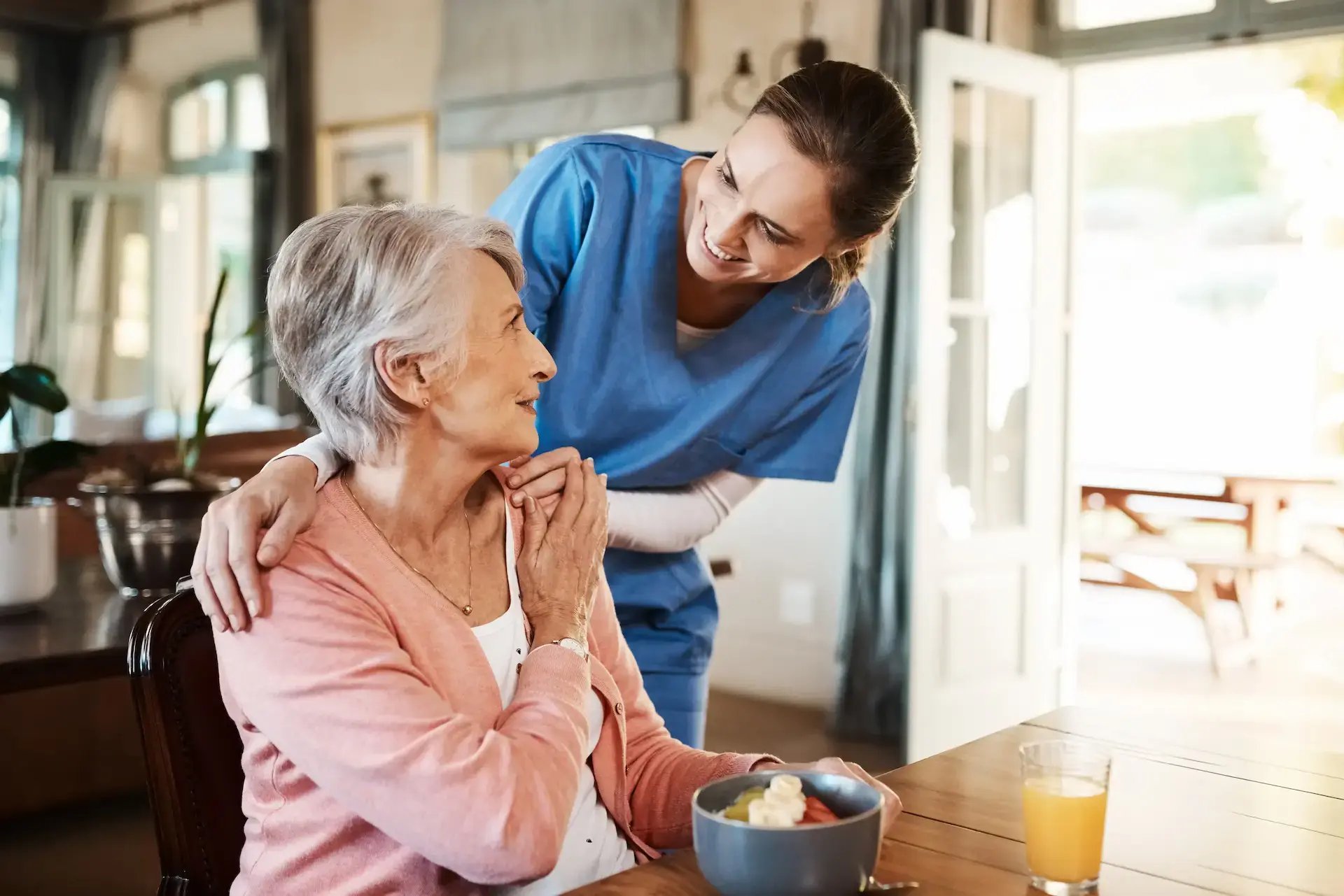 un aide-soignante faisant un geste tendre et souriant à une patiente