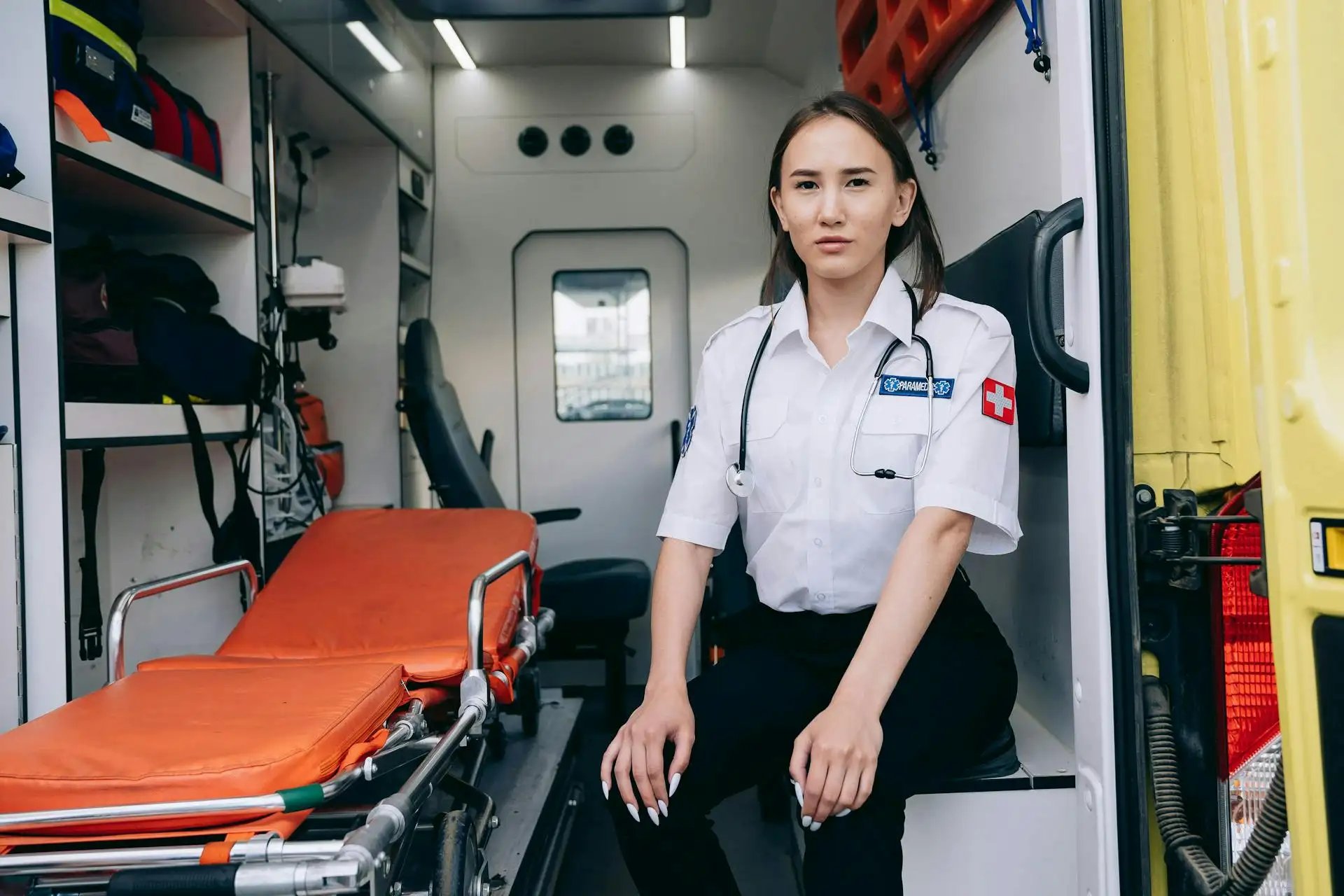 ambulancière assise à côté d'un brancard dans le véhicule de secours