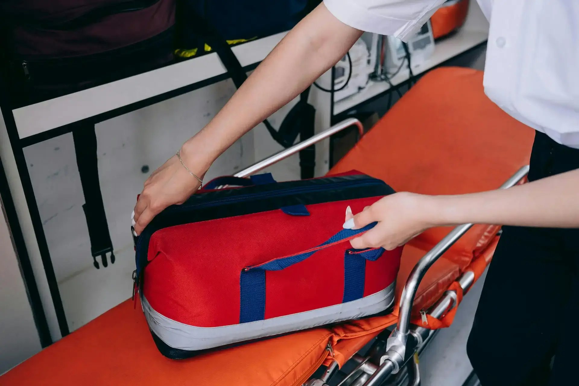 ambulancière rangeant le matériel dans sa trousse de secours sur un brancard dans l'ambulance