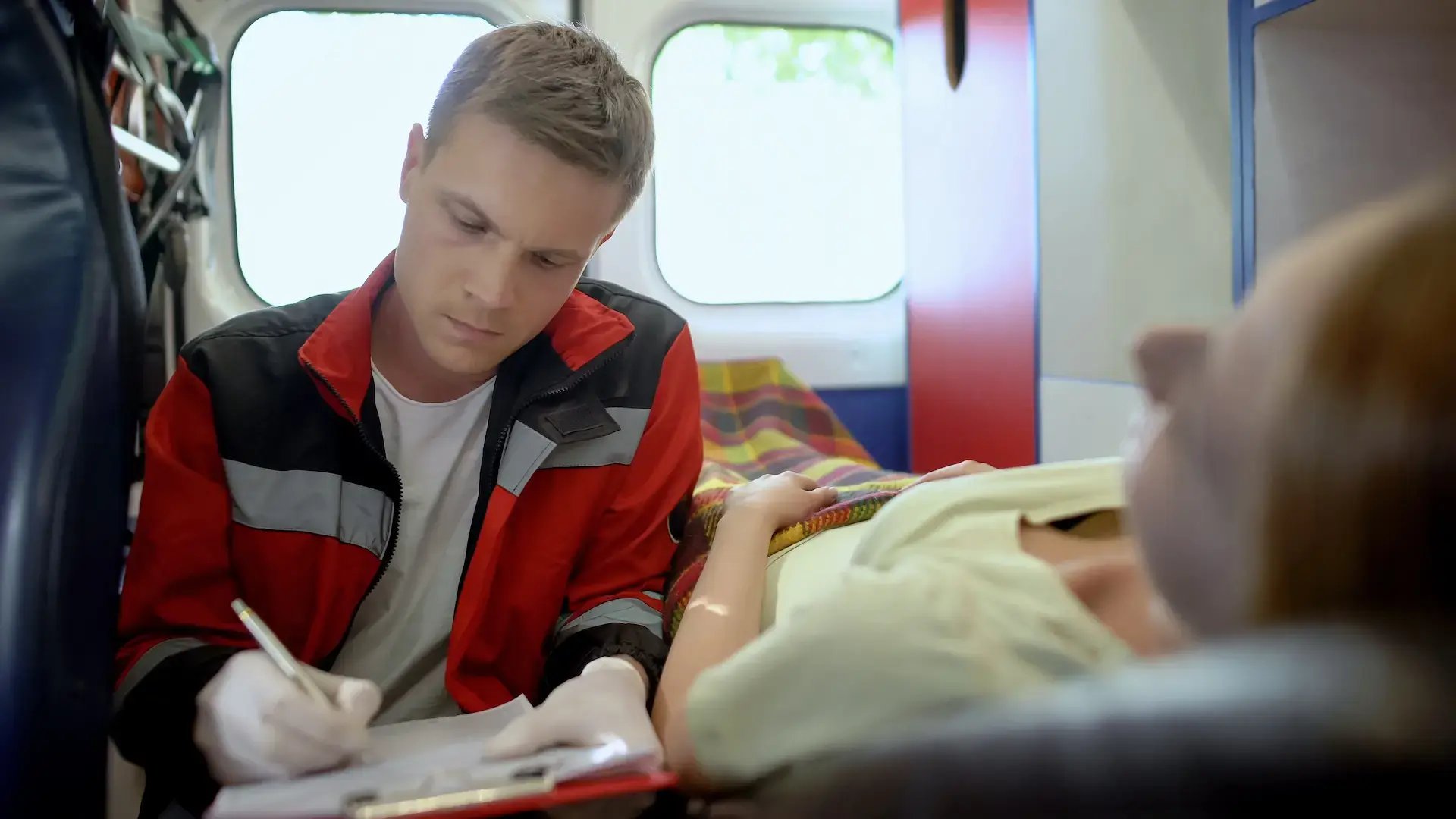 un ambulancier posant des questions à son patient sur le brancard