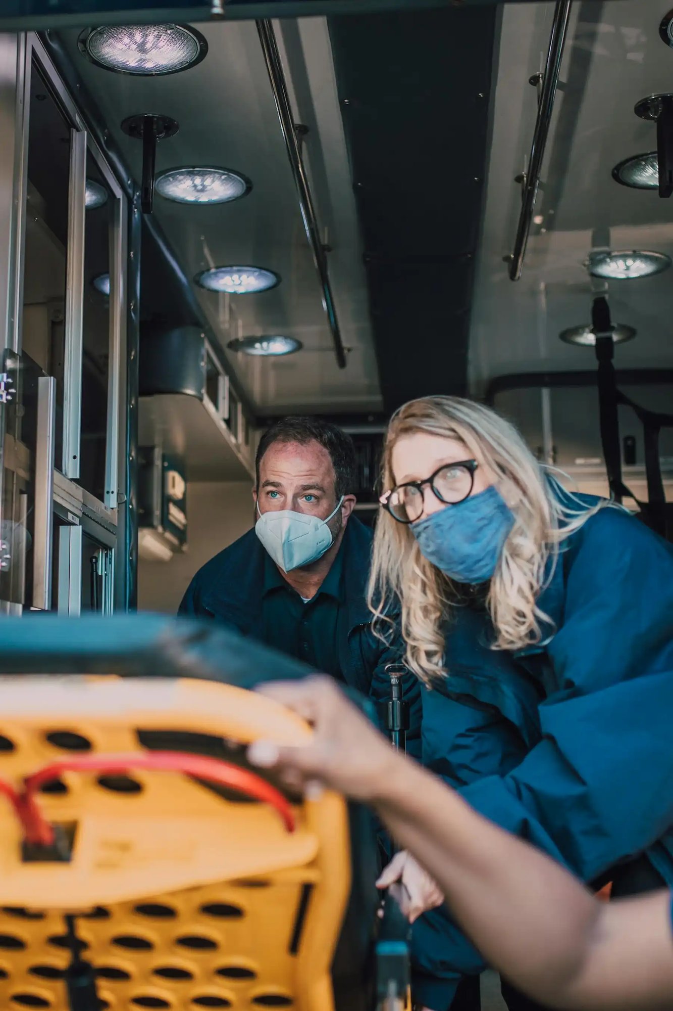 deux ambulanciers masqués discutant avec un patient sur le brancard