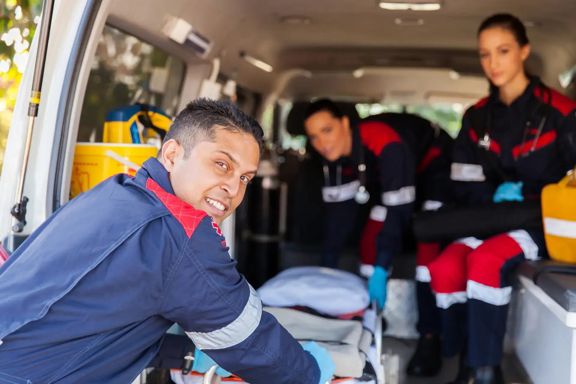 trois ambulanciers montant dans leur véhicule avec un brancard