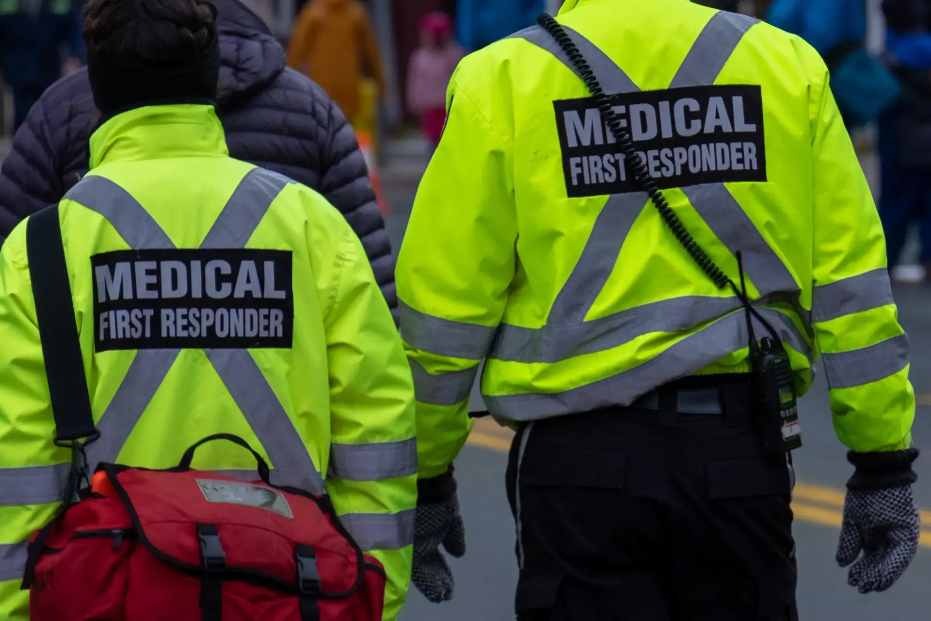 deux ambulanciers marchant de dos en gilets jaunes avec écrit "medical first responder"