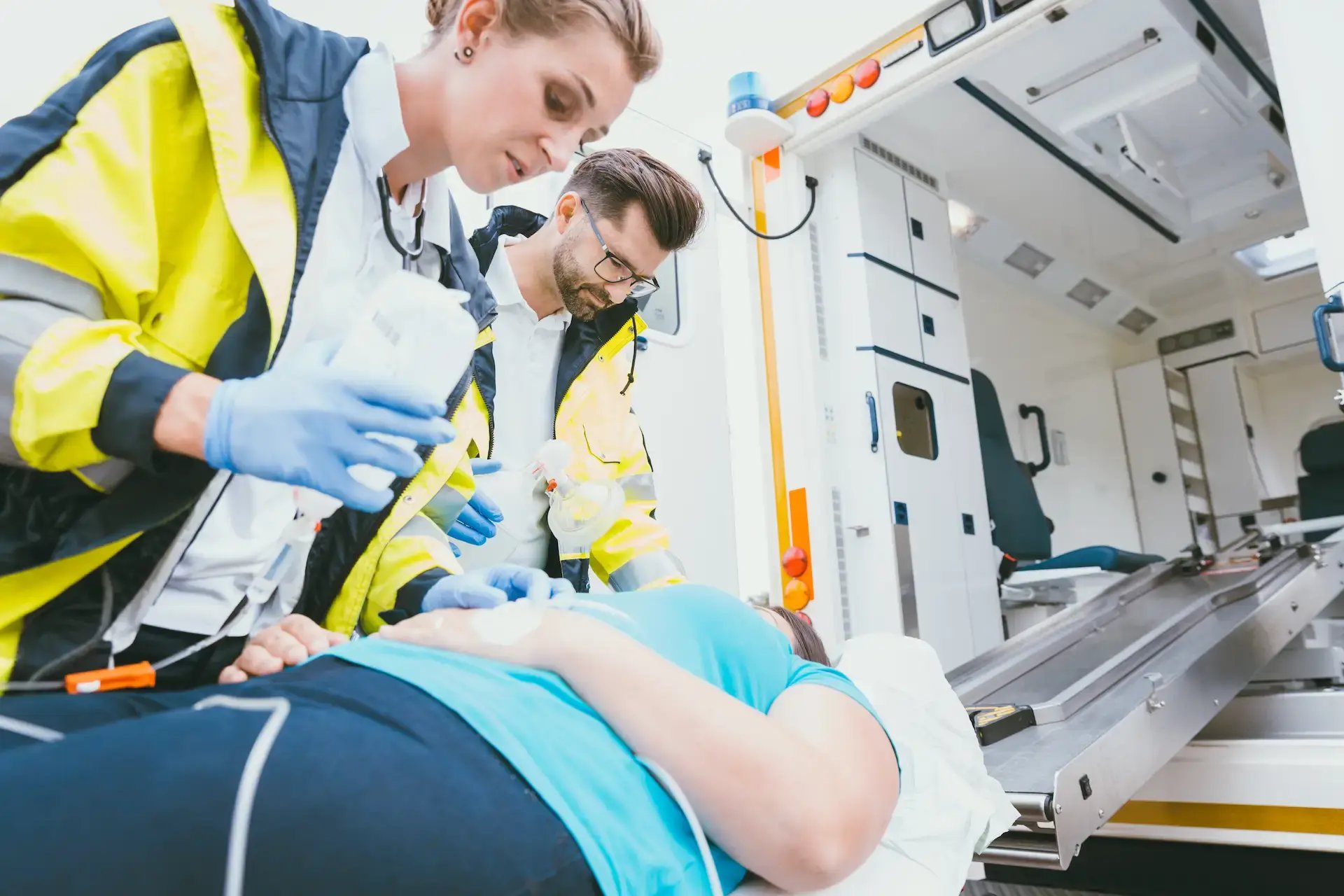 deux ambulanciers prenant en charge leur victime en la faisant monter dans le véhicule sur un brancard
