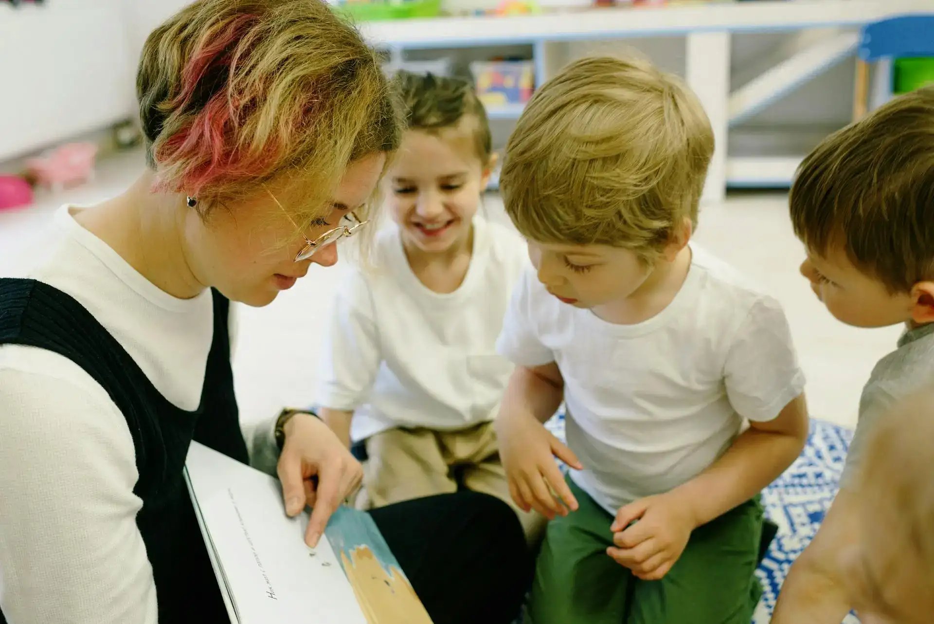 assistant qui lit un livre aux enfants qu'elle garde