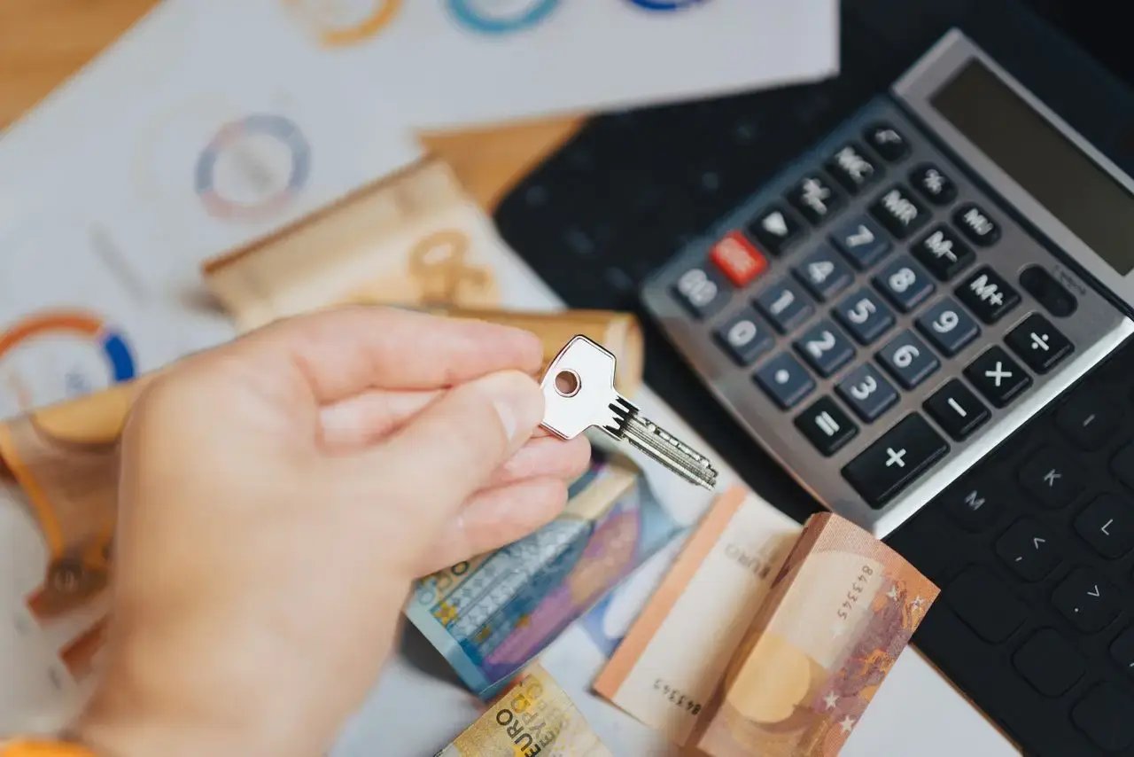 Une main présente une clé au-dessus d'argent et d'une calculatrice