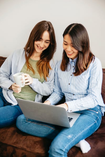 cheerful-women-browsing-laptop-couch cheerful-women-browsing-laptop-couch
