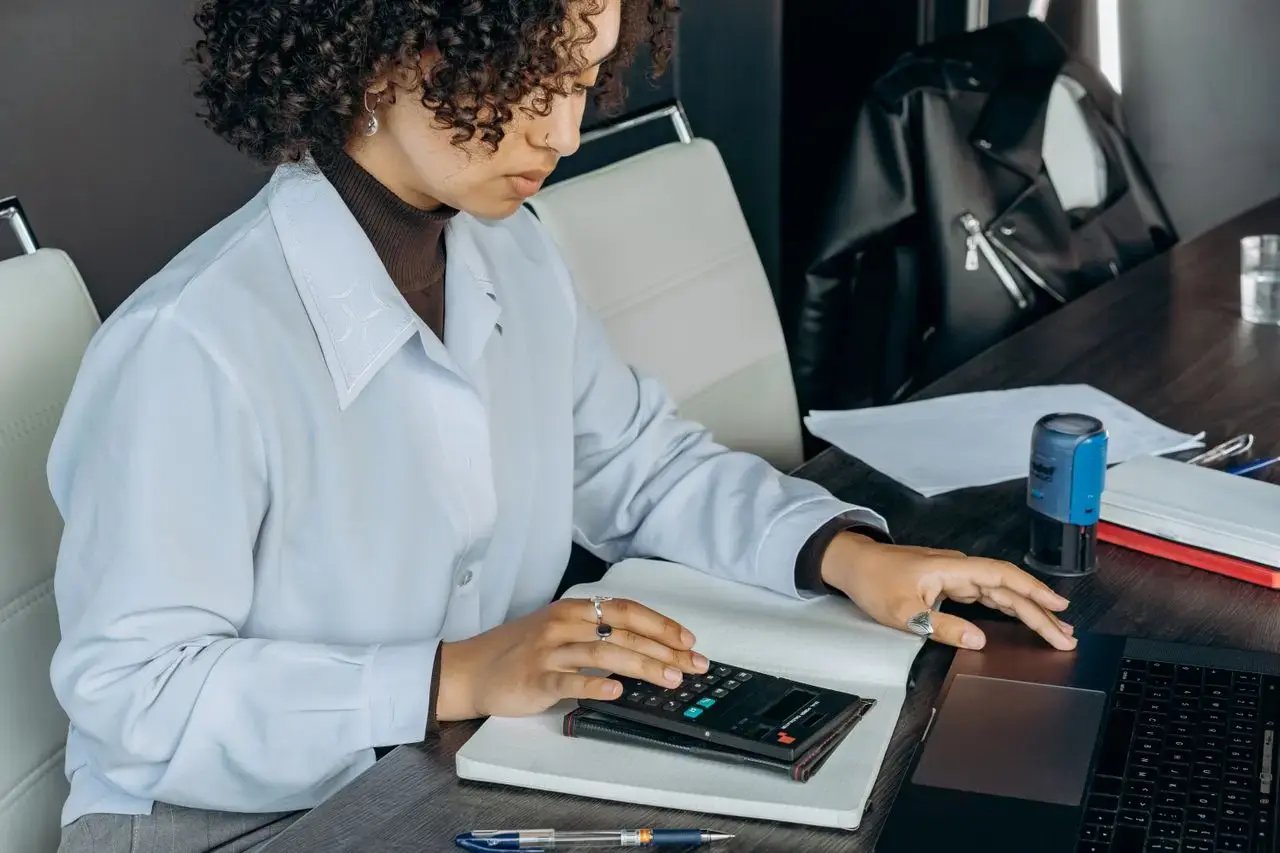 Une femme fait un calcul devant son ordinateur 