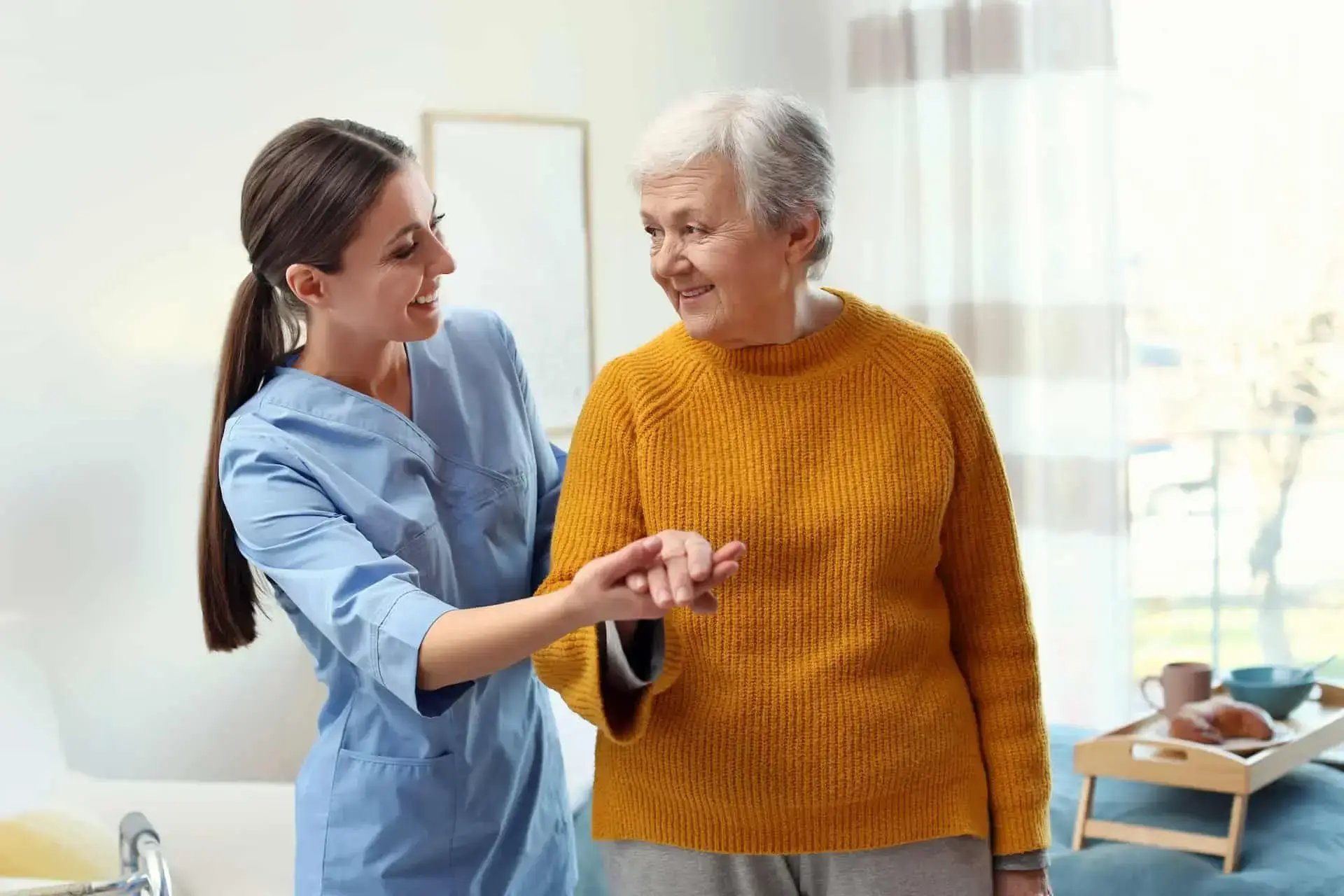 une aide-soignante accompagnant une patiente en lui donnant la main