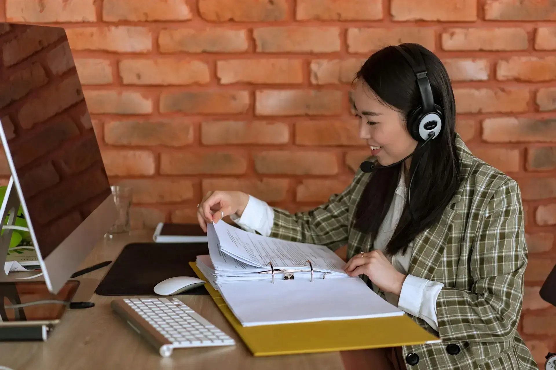 femme avec un casque lisant des documents à son bureau 