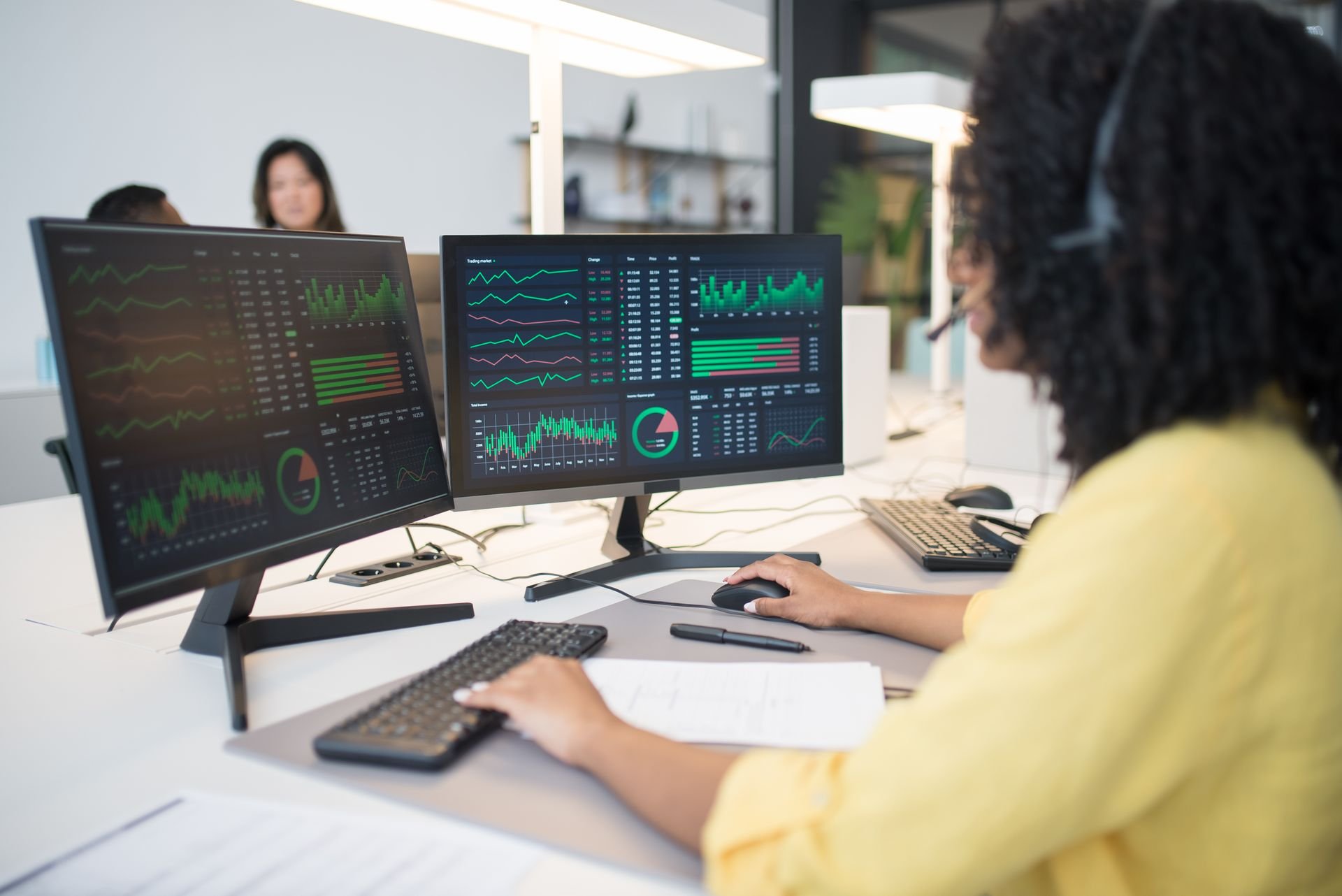 femme avec deux ecrans travaillant sur des statistiques