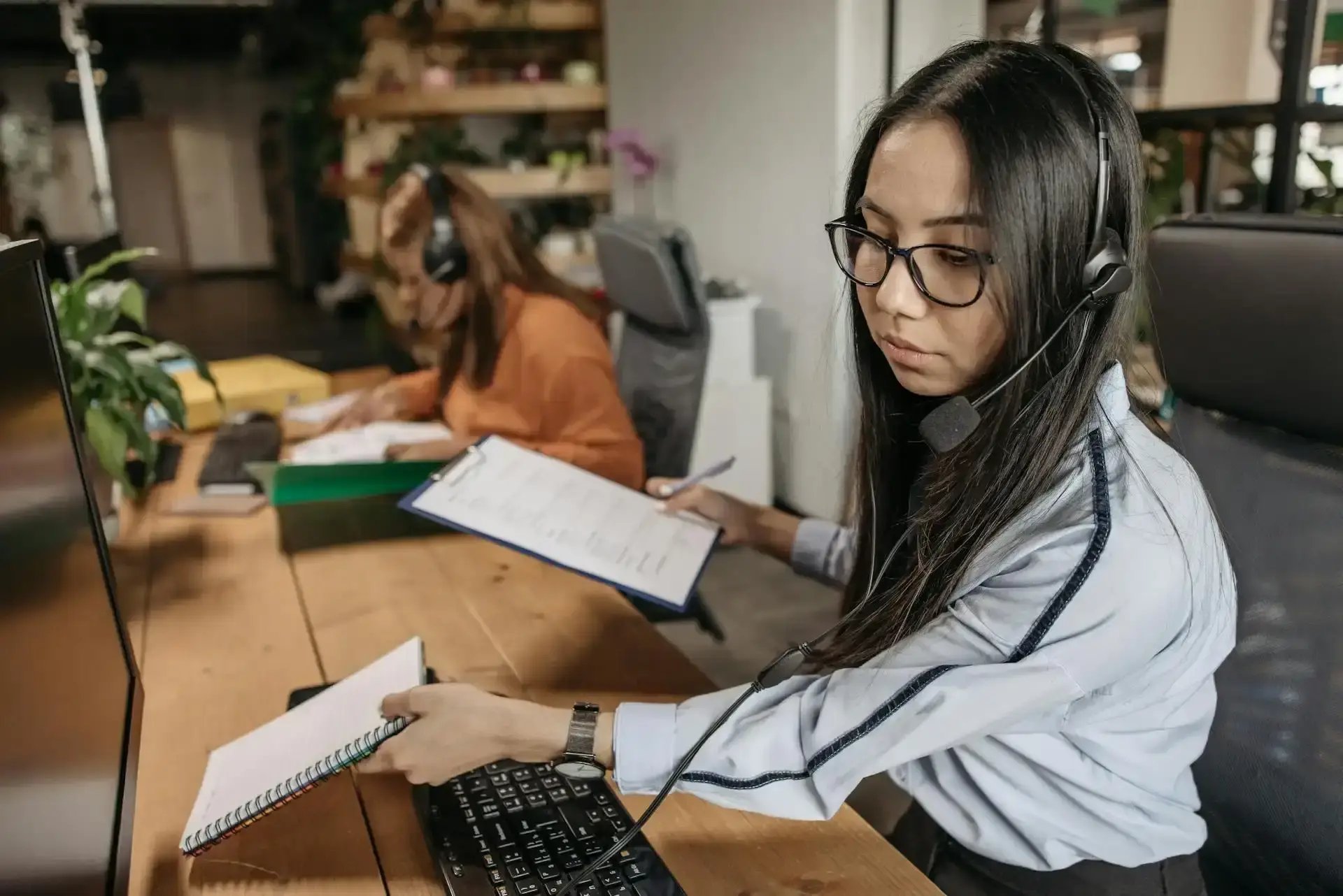 une assistante rh à son bureau avec un casque aux oreilles et des documents à la main
