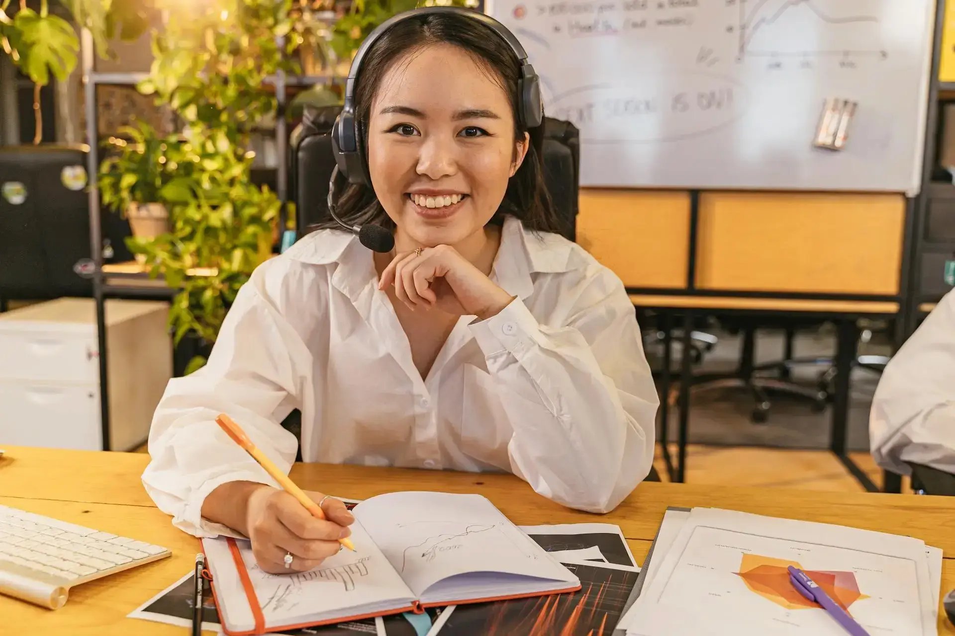 femme souriant et dessinant des graphiques sur un carnet 