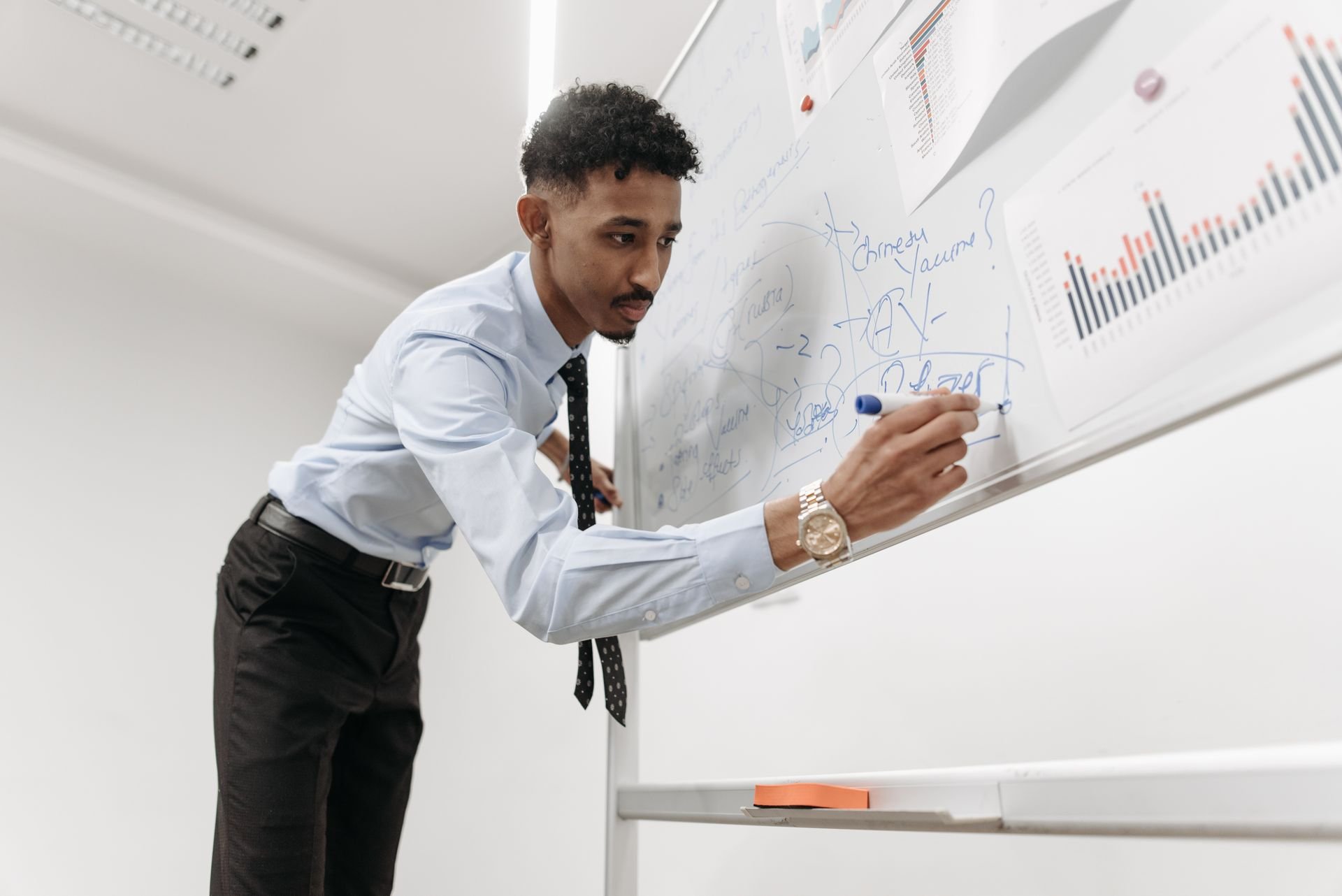 homme écrivant sur un tableau effaçable avec un marqueur