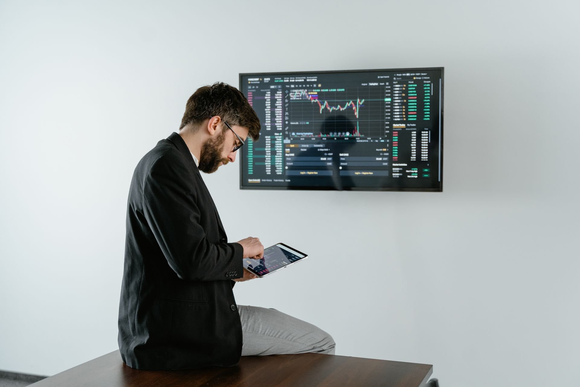 homme travaillant sur sa tablette et un écran au mur