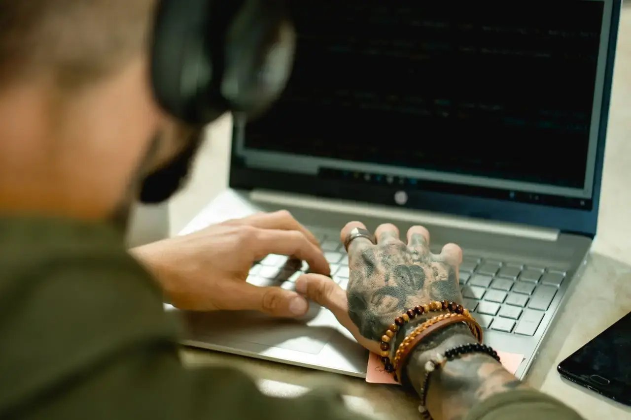 Un homme tatoué travaille sur son ordinateur