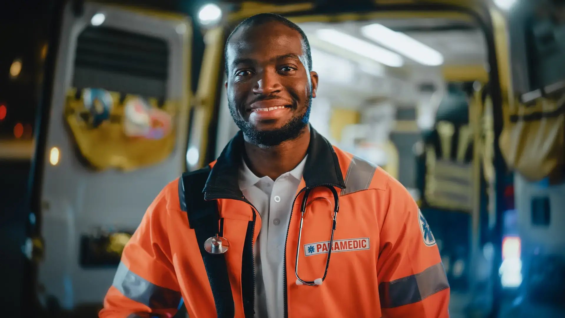 un paramédical souriant, posé devant son véhicule de secours