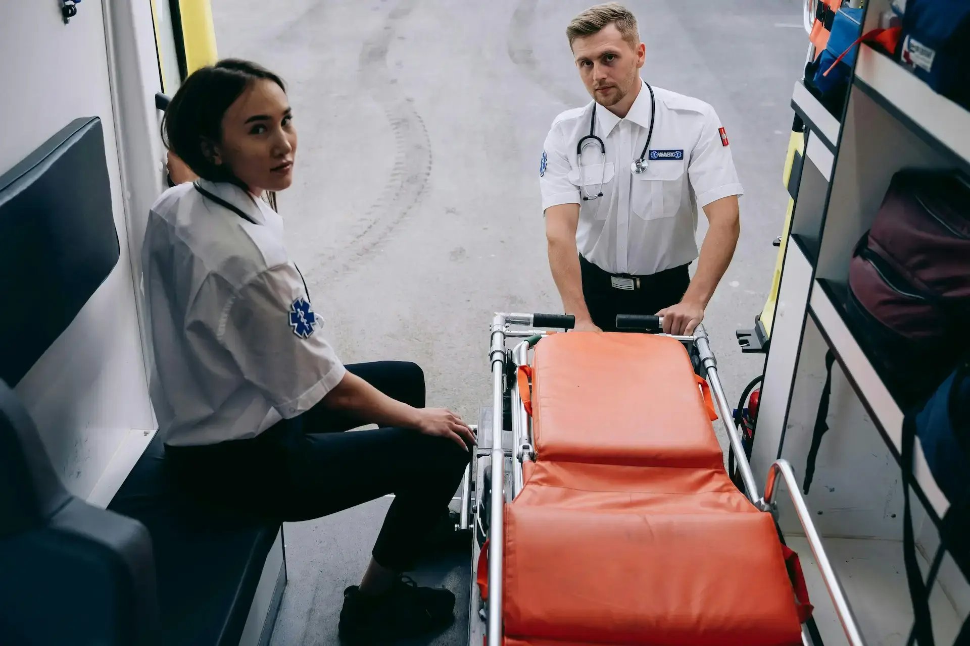 deux paramédicaux rentrent le brancard dans le véhicule