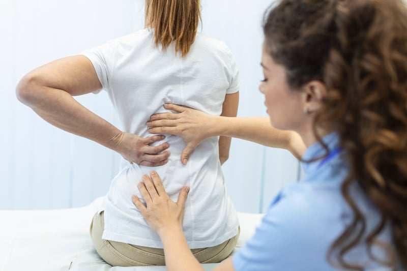 Physiothérapeute auscultant une patiente femme souffrant de maux de dos