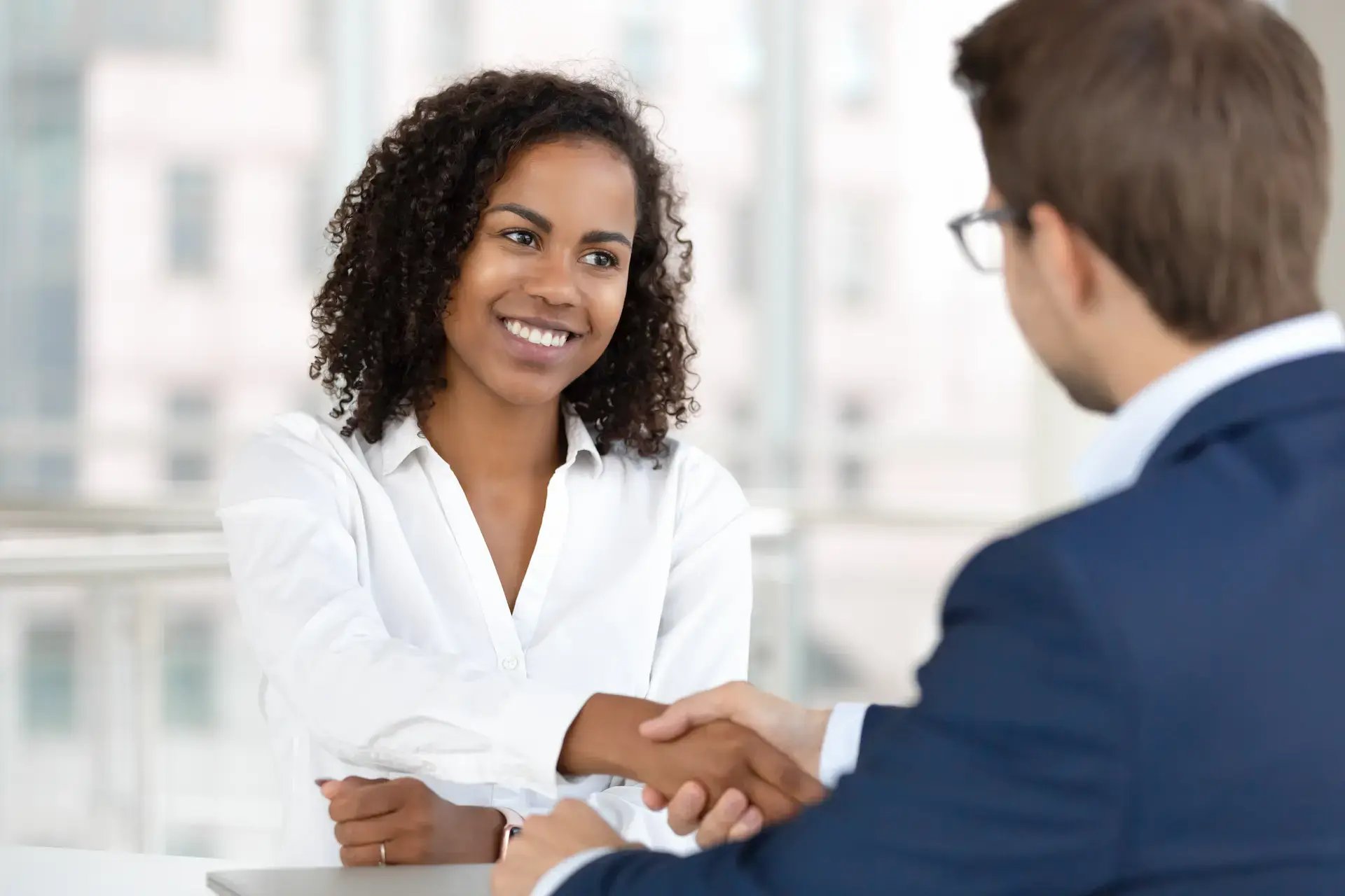 femme souriant et serrant la main à un homme en face d'elle