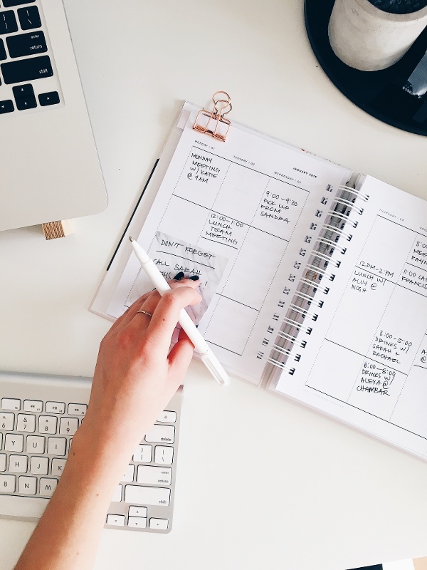 Une femme travaille sur un bureau et écrit sur un agenda